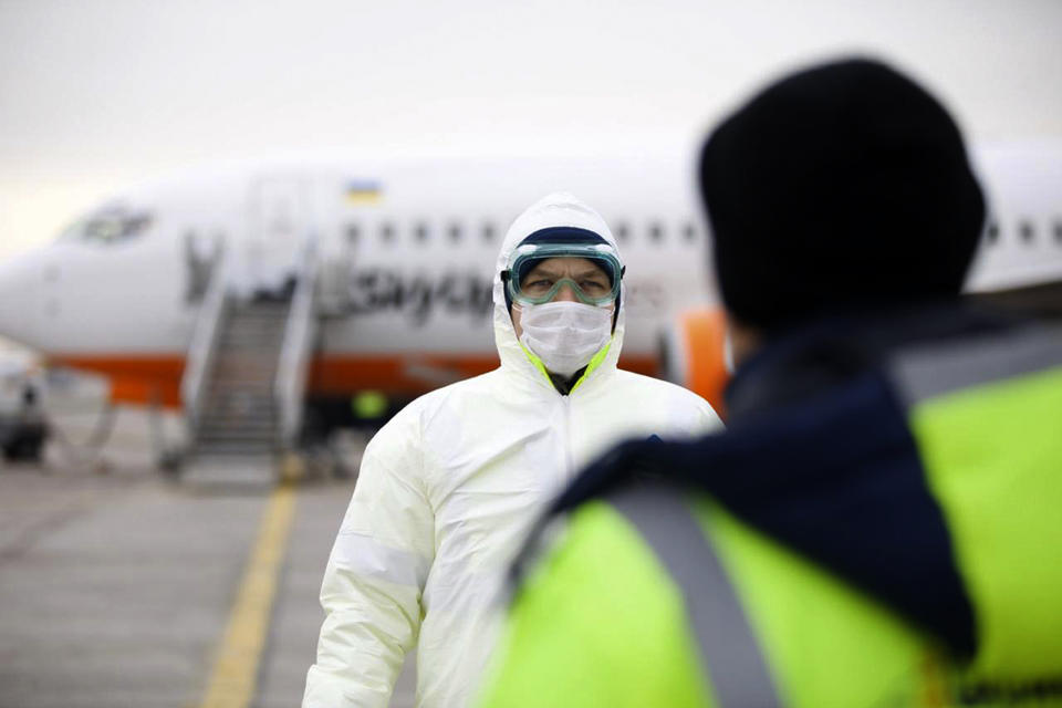 In this handout photo provided by the Ukrainian Presidential Press Office, a member of medical personnel stands ready at the Ukrainian aircraft chartered by the Ukrainian government for evacuation from the Chinese city of Wuhan, lands at Borispil international airport outside Kyiv, Ukraine, Thursday, Feb. 20, 2020. A plane carrying evacuees from Wuhan, including over 45 Ukrainians and a number of foreign passengers landed ahead of a 14-day quarantine in the country. (Ukrainian Presidential Press Office via AP)