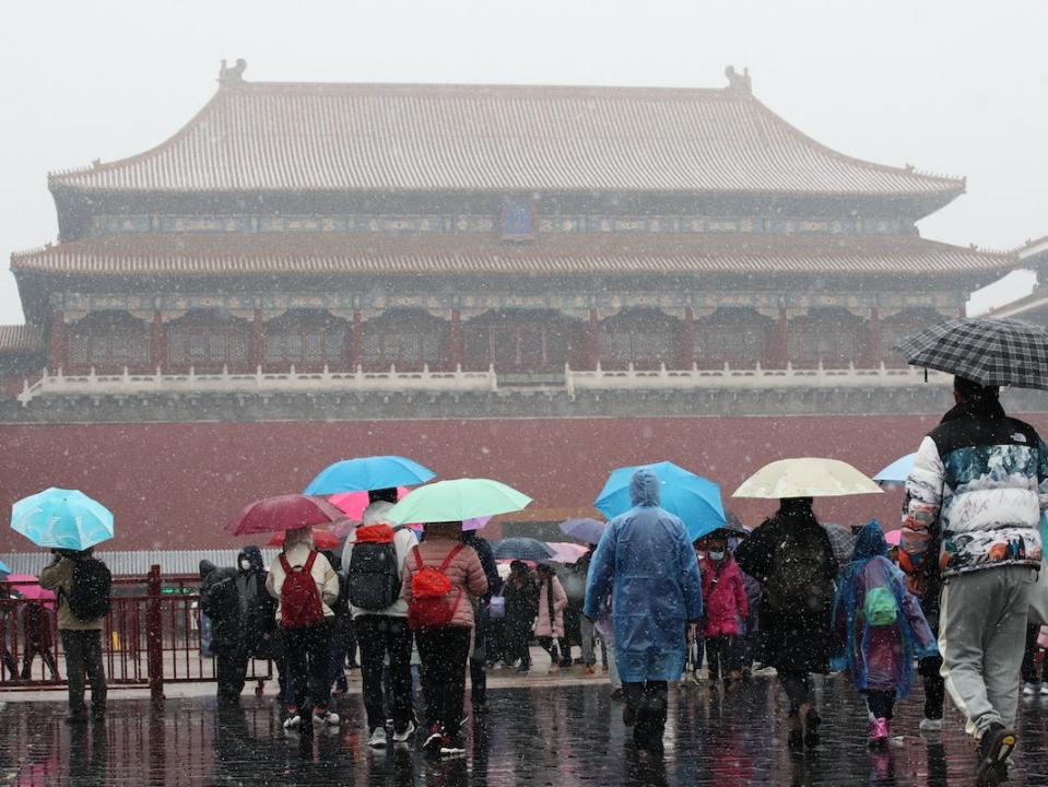 People holding umbrellas visit the Forbidden City during the first snow of the season on November 21, 2020