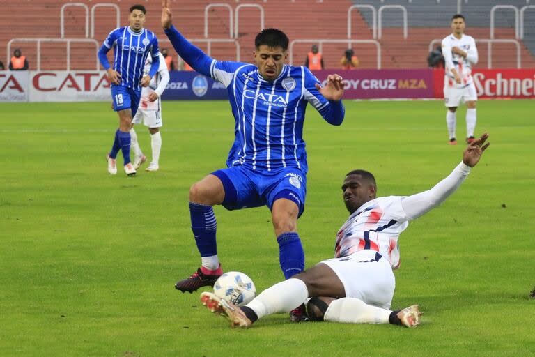 Jhohan Romaña va al piso para quitarle el balón a Nahuel Ulariaga, el autor del gol de Godoy Cruz; todos se quedaron con ganas de más en Mendoza.