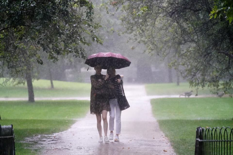 Two women walk through heavy rain (Victoria Jones/PA) (PA Wire)