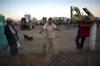 FILE - In this Wednesday, Jan. 4, 2017, file photo, security guard Jose Guadalupe Gonzalez, left, and other guards watch over the remaining heavy machinery at the Ford construction site, one day after Ford canceled plans to build a plant in Villa de Reyes, outside San Luis Potosi, Mexico. Ford said declining sales of small cars, not President Donald Trump, influenced the Mexico plant decision, and the company will still make the Focus in Mexico at a different plant. (AP Photo/Rebecca Blackwell, File)