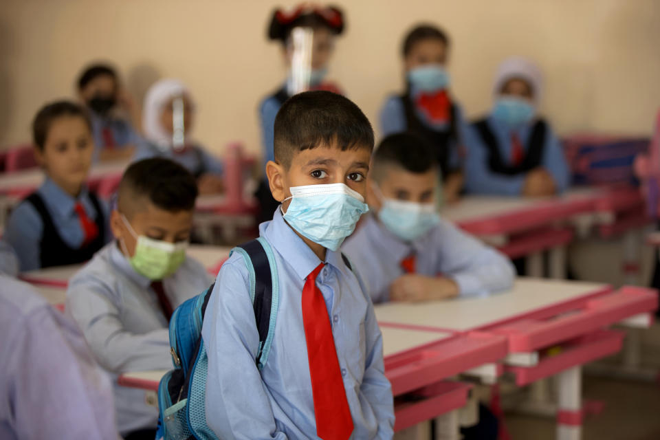 Students wear face masks in their classroom, in Baghdad, Iraq, Monday, Nov. 1, 2021. Across Iraq, students returned to classrooms Monday for the first time in a year and a half – a stoppage caused by the coronavirus pandemic - amid overcrowding and confusion about COVID-19 safety measures. (AP Photo/Hadi Mizban)