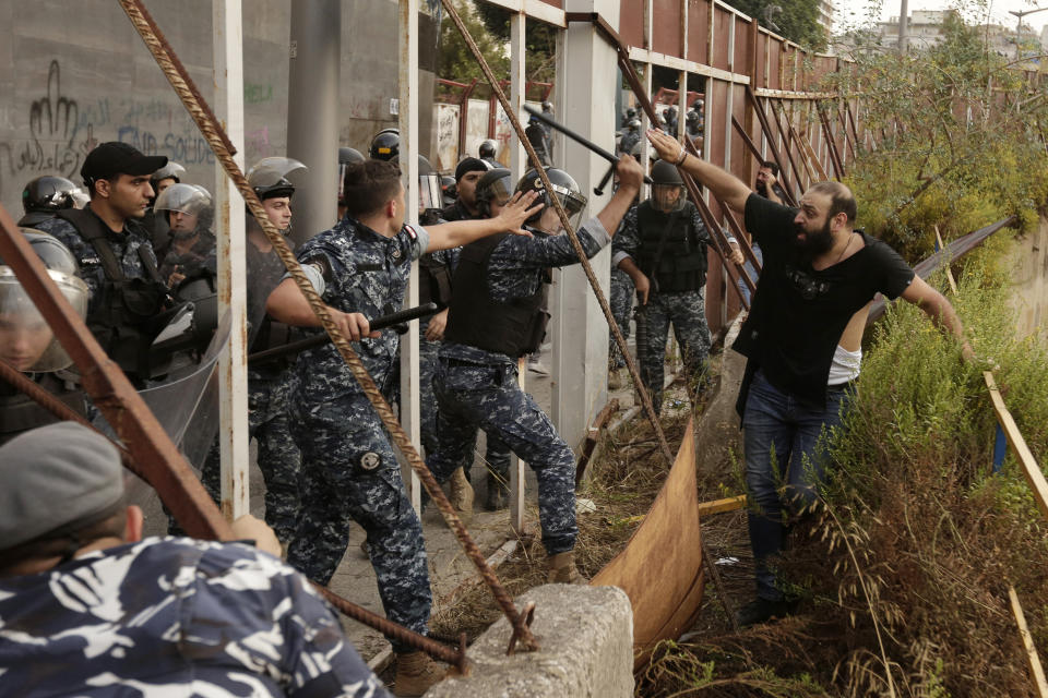 Lebanese riot policemen pursue a Hezbollah supporter after a clashes erupted between anti-government protesters and Hezbollah supporters during a protest in Beirut, Lebanon, Friday, Oct. 25, 2019. Leader of Lebanon's Hezbollah calls on his supporters to leave the protests to avoid friction and seek dialogue instead. (AP Photo/Hassan Ammar)