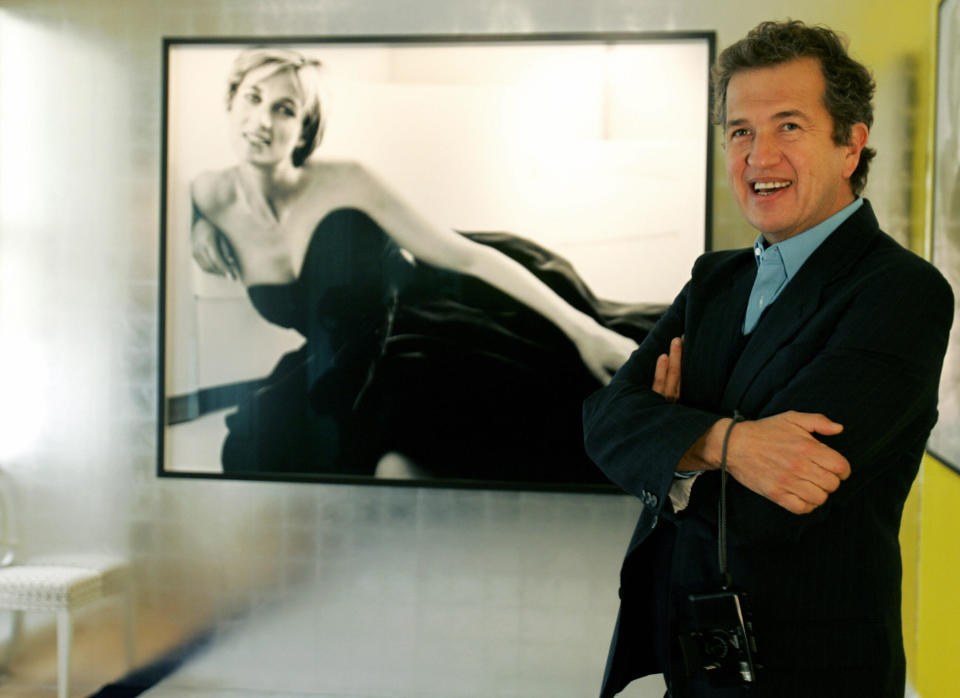LONDON, United Kingdom:  Celebrity portrait photographer Mario Testino poses in front of one of the pictures he took of the late British Princess Diana at an exhibition in Kensington Palace in London, 22 November 2005. Some of the portraits to be exhibited have never been displayed in public before. Also on show will be nine of Diana's gowns, four of which are featured in his portraits. AFP PHOTO/CARL DE SOUZA  (Photo credit should read CARL DE SOUZA/AFP via Getty Images)