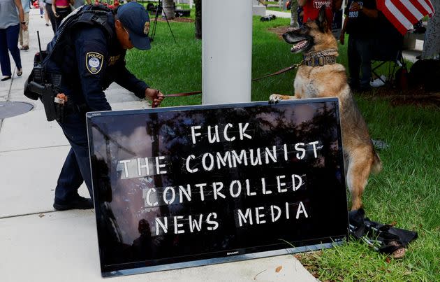 A police officer and a police dog are seen next to a sign reading 