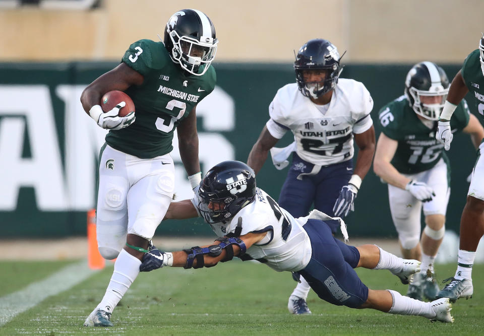 EAST LANSING, MI – AUGUST 31: LJ Scott #3 of the Michigan State Spartans tries to run through the tackle of Gaje Ferguson #23 of the Utah State Aggies at Spartan Stadium on August 31, 2018 in East Lansing, Michigan. (Photo by Gregory Shamus/Getty Images)