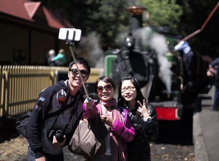 Tourists take a "selfie" picture in front of Puffing Billy steam engine 6A during a water stop at Lakeside station near Melbourne, October 20, 2014. REUTERS/Jason Reed