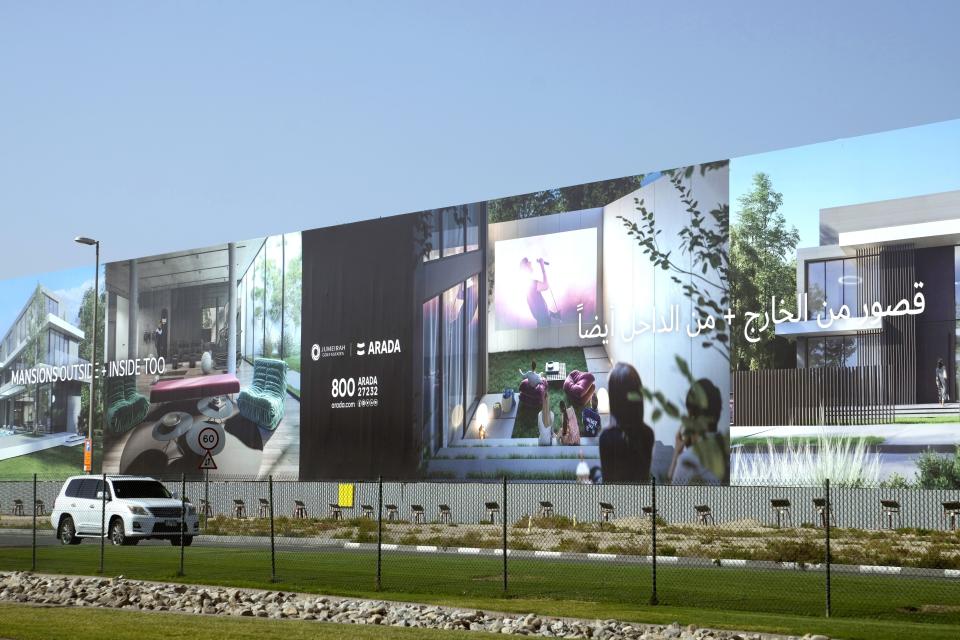 A car passes by a giant billboard, advertising a new development in Dubai, United Arab Emirates, Wednesday, Feb. 1, 2023. For the first time since a 2009 financial crisis nearly brought Dubai to its knees, several major abandoned real estate projects now show signs of life. As with its other booms, war again is driving money into Dubai and buoying its economy. This time it's Russian investors fleeing Moscow’s war on Ukraine, rather than people escaping Mideast battlefields. (AP Photo/Kamran Jebreili)