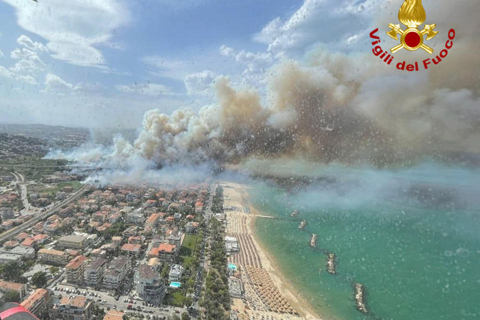 In this photo released by the Italian Firefighters, a view of a violent wildfire that burned the historical pinewood in Pescara, central Italy, Sunday, Aug. 1, 2021. Sea resorts customers were seen running away as the flames were approaching the beach. More than 100 people were evacuated from their houses. A heat wave across southern Europe, fed by hot air from North Africa, has led to wildfires across the Mediterranean, including on the Italian island of Sicily and in western Greece. (Italian Firefighters via AP)