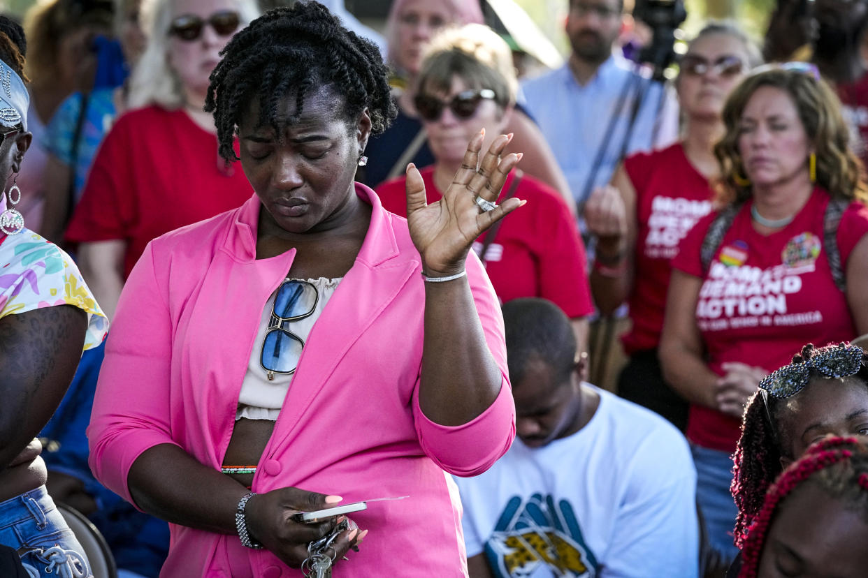 Image: A woman attending a vigil for the victims of Saturday's mass shooting bows her head in prayer on Aug. 27, 2023, in Jacksonville, Fla. (John Raoux / AP)