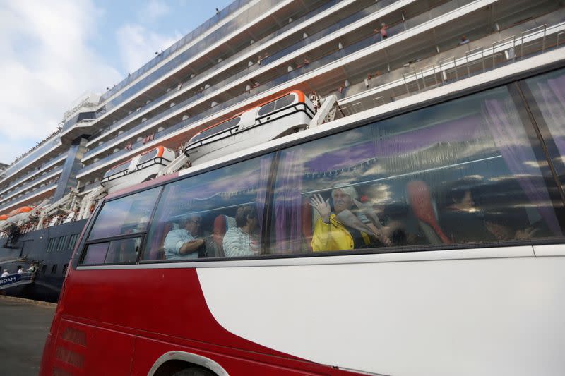 Passengers wave as they leave MS Westerdam, a cruise ship that spent two weeks at sea after being turned away by five countries over fears that someone aboard might have the coronavirus, as it docks in Sihanoukville