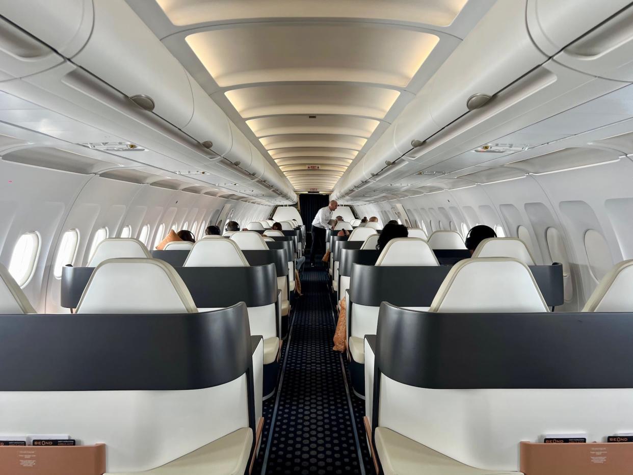 A view of the Beond cabin from the back with a flight attendant serving meals.