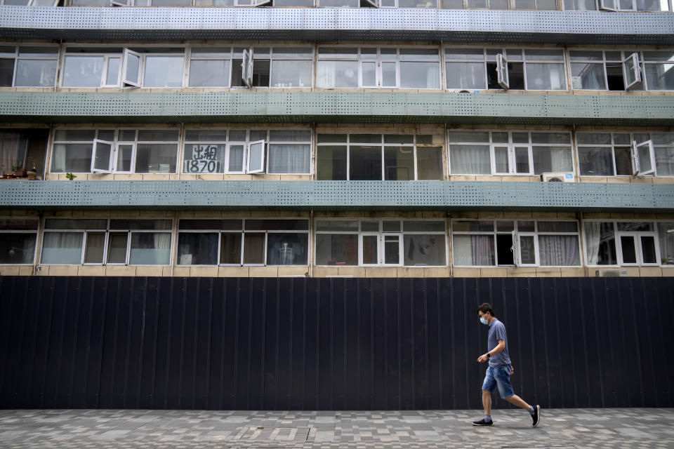 A man wearing a face mask walks past a residential building that has been surrounded by metal barricades as part of COVID-19 controls in Beijing, Tuesday, June 14, 2022. The mayor of a northeastern Chinese city on the North Korean border that has been under lockdown for more than 50 days has apologized for failures in his administration's work amid widespread, but often disguised, dissatisfaction over the government's heavy-handed approach to handling the pandemic. (AP Photo/Mark Schiefelbein)