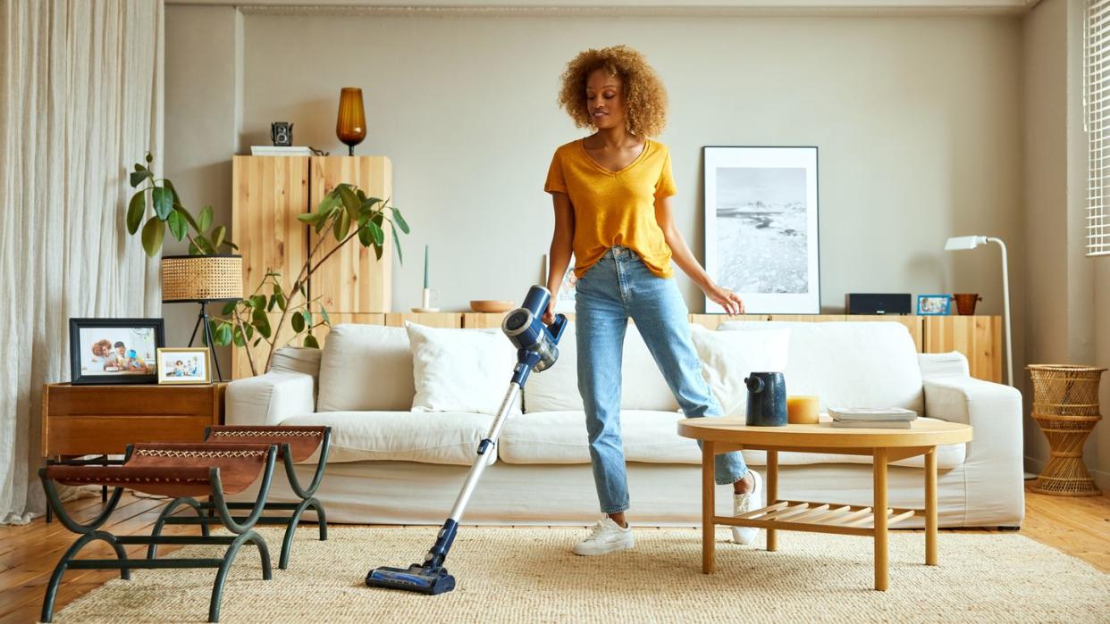 woman cleaning carpet with vacuum cleaner at home