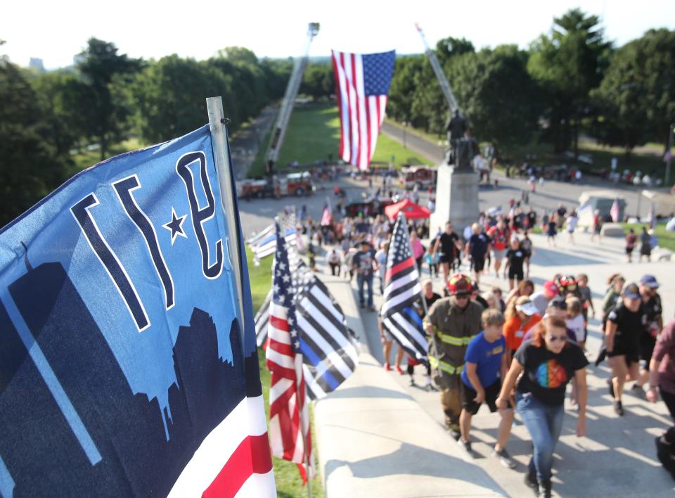 People pass a 9/11 flag during the Memorial Climb on the steps of the McKinley Presidential Library & Museum in Canton on Saturday. The event marked the 20th anniversary of the 9/11 attacks and recalled the memory of the 343 firefighters who lost their lives that day.
