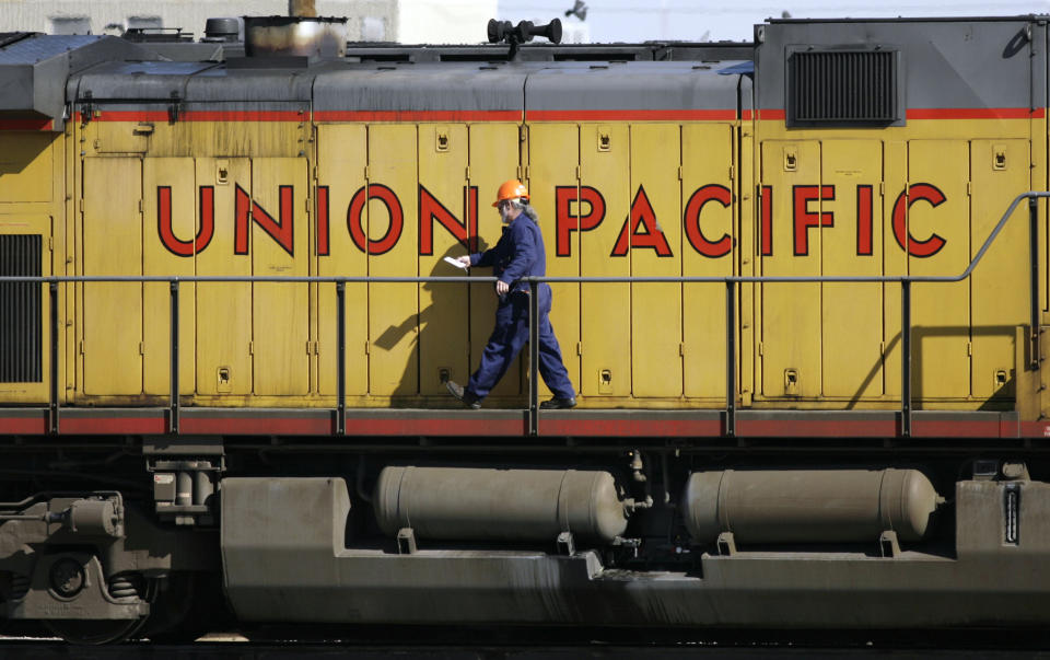 FILE - A maintenance worker walks on the side of a locomotive in the Union Pacific Railroad fueling yard in north Denver, Oct. 18, 2006. Union Pacific will renew its push for one-person train crews later this summer when the railroad tests out the idea of having a conductor in a truck respond to problems on trains in Nebraska and Colorado. UP's Jason Pinder confirmed the pilot program Monday, July 17, 2023, when he testified against a proposed Kansas rule that would require two-person crews. (AP Photo/David Zalubowski, File)