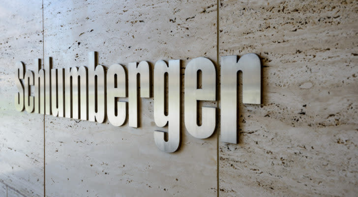 A zoomed in image of the logo for "Schlumberger" reflecting light on a smooth tan stone tiled wall.