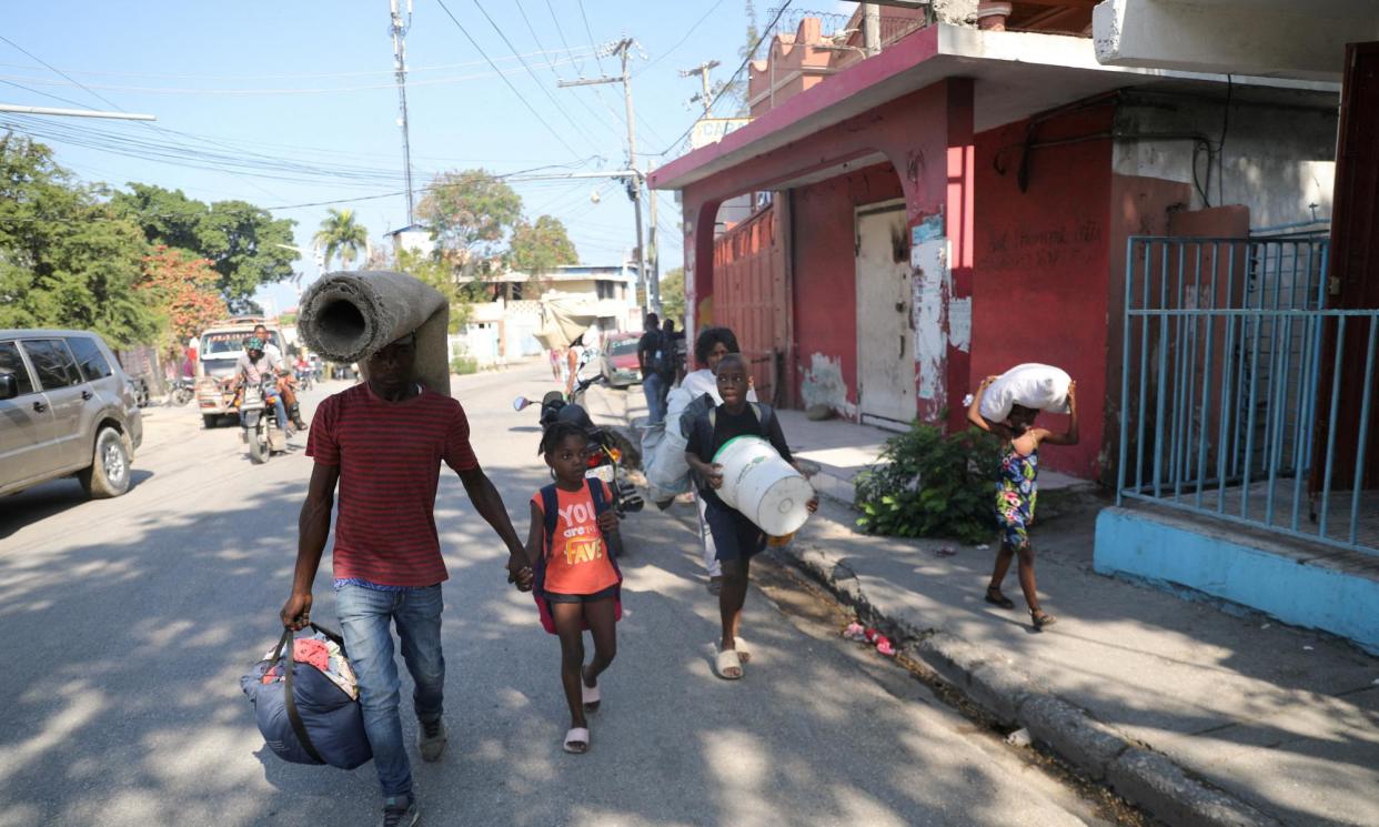 <span>People fleeing from violence around their homes walk towards a shelter with their belongings, in Port-au-Prince, Haiti, on Saturday.</span><span>Photograph: Ralph Tedy Erol/Reuters</span>