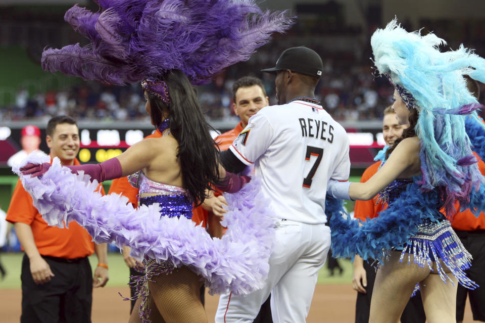 Miami Marlins shortstop Jose Reyes (7) is escorted onto the field by women in carnival costumes for an Opening Day baseball game against the St. Louis Cardinals, Wednesday, April 4, 2012, in Miami. (AP Photo/Lynne Sladky)