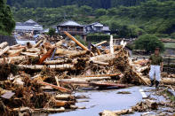 <p>A man trying to return his home gives up as driftwood block the way as torrential rain hit on July 6, 2017 in Toho, Fukuoka, Japan. (Photo: The Asahi Shimbun via Getty Images) </p>