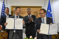 Kosovo prime minister Avdullah Hoti, front right, signs an economic agreement with head of U.S. International Development Finance Corporation Adam Boehler, front left, witnessed by U.S. presidential envoy for the Kosovo-Serbia talks Richard Grenell, back left, and Kosovo President Hashim Thaci, 2nd from right, in capital Pristina, Kosovo on Monday, Sept. 21, 2020. A high-level delegation from the Untied States visited Kosovo on Monday to discuss on how to move ahead with projects signed earlier at a White House meeting between Kosovo and Serbia to normalize their economic ties. (AP Photo/Astrit Ibrahimi)