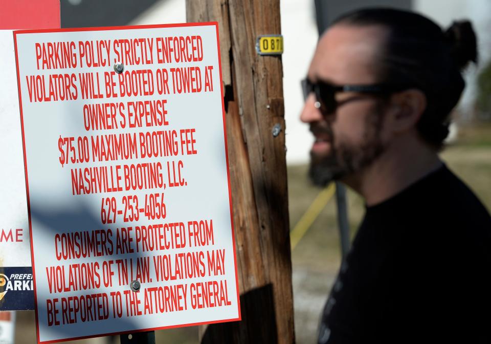 Steven Knapp stands near the parking lot where his car was booted by a private company in front of a “No Parking” sign on Monday, Feb. 5, 2024, in Nashville, Tenn. Knapp said he plans to speak at an upcoming Metro Council meeting about the companies who are booting cars and creating a predatory business practice.