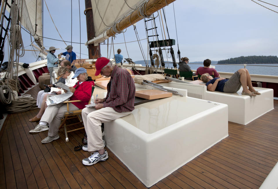 In this photo made Thursday, Aug. 2, 2012, passengers read, work on crossword puzzles, and just relax on the deck of the schooner Mary Day during a three-day cruise on Penobscot Bay off Camden, Maine. The 90-foot Mary Day, which is celebrating its 50th season, is the first schooner in the Maine windjammer fleet to be built specifically to accommodate passengers. Its sleeping cabins are heated and have nine feet of headroom. (AP Photo/Robert F. Bukaty)