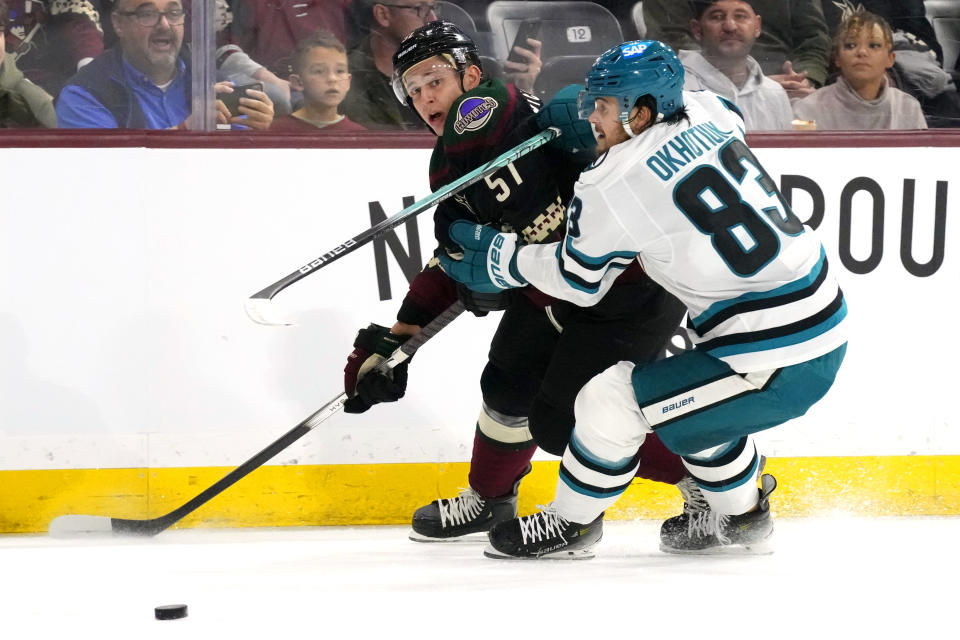 Arizona Coyotes defenseman Troy Stecher (51) passes the puck past San Jose Sharks defenseman Nikita Okhotiuk (83) during the first period of an NHL hockey game Friday, Dec. 15, 2023, in Tempe, Ariz. (AP Photo/Ross D. Franklin)