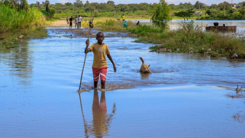 A young boy and his dog cross the flooded Athi River in Joska, Kenya - 23 April 2024 i