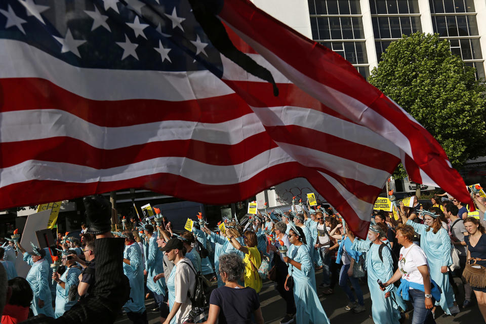 <p>Protesters dressed as the Statue of Liberty march under a US flag during a demonstration in the center of Brussels on May 24, 2017. Demonstrators marched in Brussels ahead of a visit of US President Donald Trump and a NATO heads of state summit which will take place on Thursday. (Photo: Peter Dejong/AP) </p>