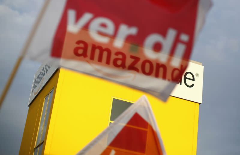A flag of German united services union Ver.di is pictured in front of the logo of Amazon on a warehouse in Bad Hersfeld