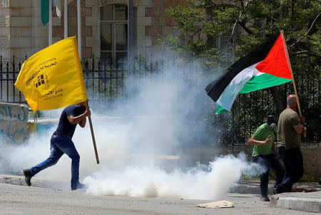 Palestinian protesters run for cover from tear gas canisters fired by Israeli troops during clashes following a protest in solidarity with Palestinian prisoners held by Israel, in the West Bank town of Bethlehem April 17, 2017. REUTERS/Ammar Awad