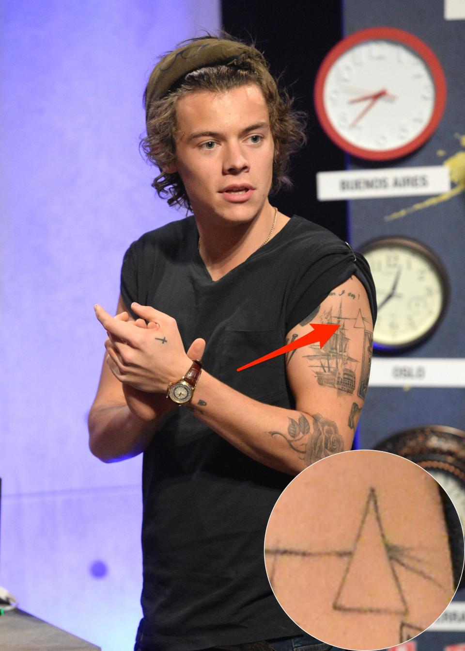 A red arrow pointing to Harry Styles' prism tattoo on his left bicep.