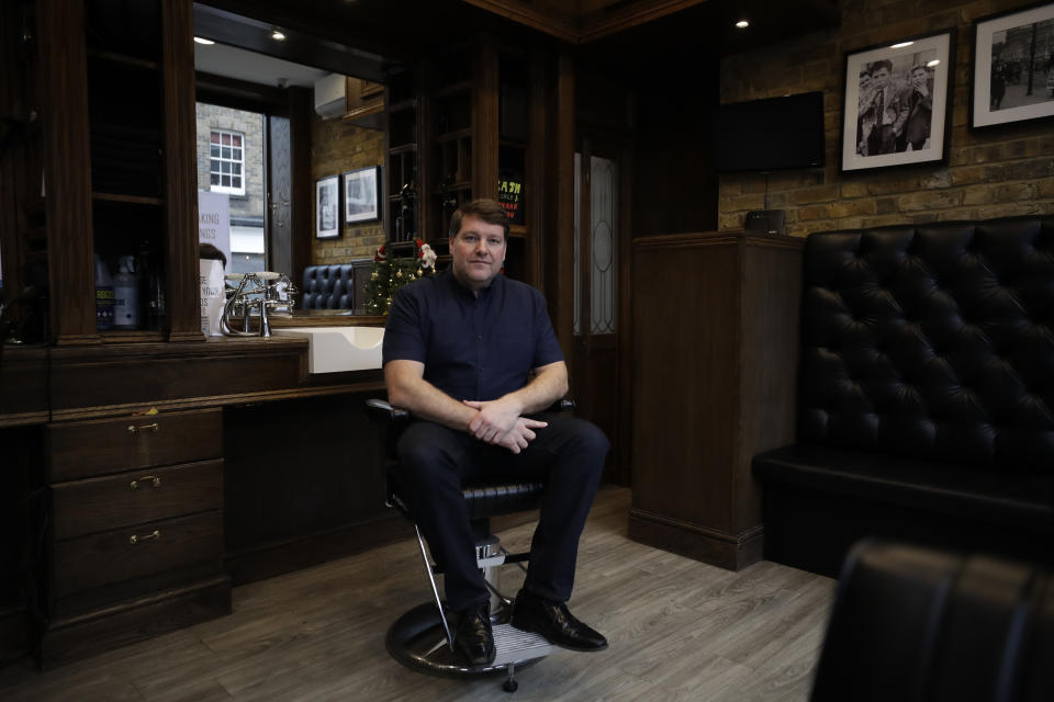 Barber Matthew Jones poses for photographs inside his 'Sharpes Barbers', which is temporarily closed as part of England's second coronavirus lockdown, on Broadway Market in Hackney, east London, Tuesday, Nov. 17, 2020. The London barber shop was busy cutting hair, Matthew laughing with colleagues and customers, when the news that the business would have to close because of the coronavirus for the second time landed.(AP Photo/Matt Dunham)