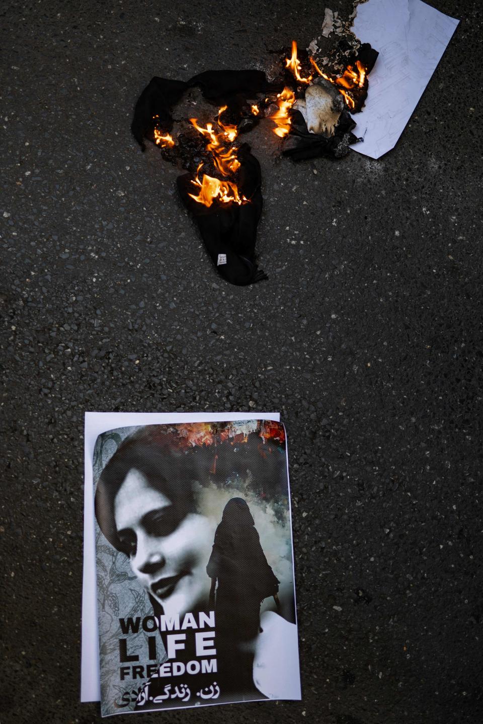 This general view shows material on fire beside a portrait of Iranian Mahsa Amini on the road during a rally outside the Iranian consulate in Istanbul on Sept. 29, 2022.