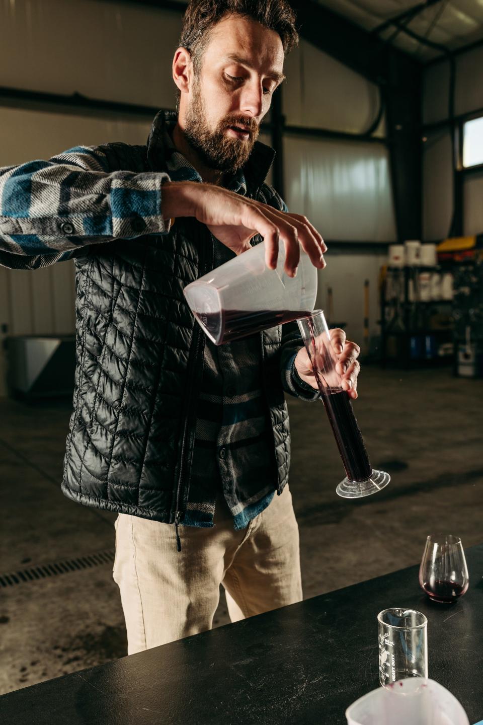 Man pouring wine into graduated cylinder from beaker