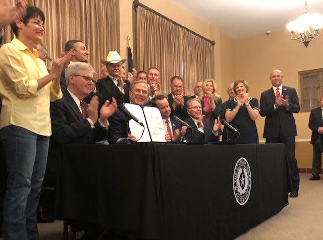 A smiling Gov. Greg Abbott signs a package of gun rights bills during a ceremony at the Alamo in San Antonio, June 17, 2021.