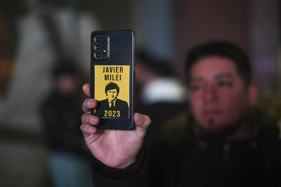 A Follower of Javier Milei, presidential candidate of the Liberty Advances coalition, takes a photograph with his phone, outside his campaign headquarters after polling stations closed during primary elections in Buenos Aires, Argentina, Sunday, Aug. 13, 2023. (AP Photo/Mario De Fina)