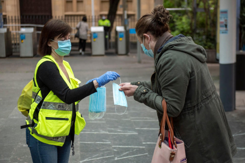 A woman in Spain's San Sebastian hands out masks to the public as lockdown measures are eased. Source: Getty