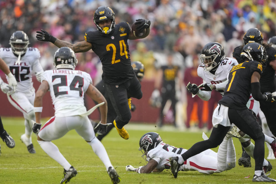 Washington Commanders running back Antonio Gibson (24) goes airborne after getting stopped by Atlanta Falcons cornerback Dee Alford (37) during the second half of an NFL football game, Sunday, Nov. 27, 2022, in Landover, Md. (AP Photo/Alex Brandon)