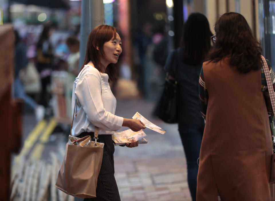 In this photo taken Thursday, Nov. 7, 2019, district council candidate Cathy Yau distributes flyers to pedestrians during her campaign at Causeway Bay in Hong Kong. Yau. a former police officer, grew exasperated as police used more force to quell the unrest. She quit the force in July after 11 years and is running in Sunday's district polls that are widely expected to deliver a decisive victory for the six-month-old movement seeking democratic reforms in the semi-autonomous Chinese territory. (AP Photo/Dita Alangkara)