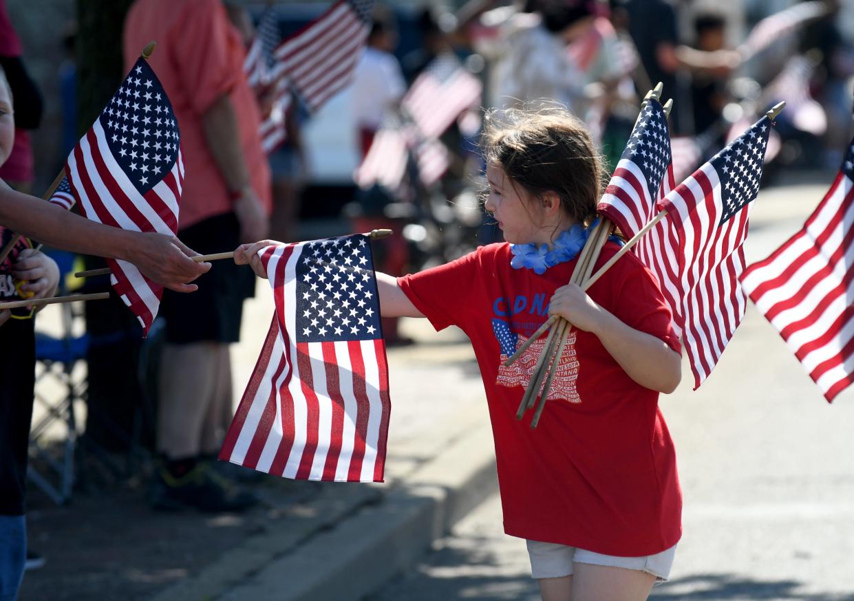 Serenity Reynolds, a Girl Scout with Troop 60377 in Canton, passes out flags along Tuscarawas Street W during the 2022 Canton Memorial Day Parade and Ceremony.