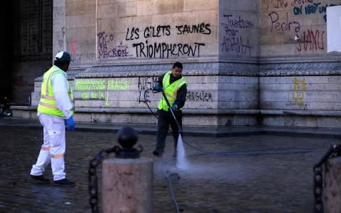 Municipal employees clean the ground in front of the Arc of Triomphe - Credit: GEOFFROY VAN DER HASSELT/AFP/Getty Images