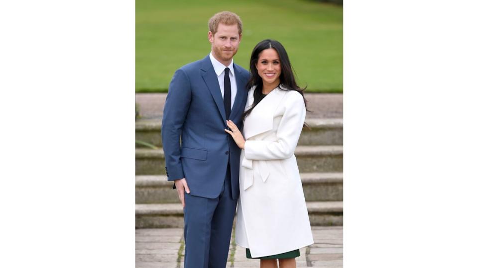 Prince Harry in a blue suit and Meghan Markle in a white overcoat