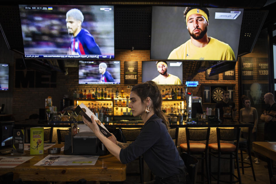 A woman reads a menu in a restaurant in Irbil, Iraq, Tuesday, March 21, 2023. The Kurdish in Iraq region won de facto self-rule in 1991 when the United States imposed a no-fly zone over it in response to Saddam's brutal repression of Kurdish uprisings. With American invasion 20 years ago much of Iraq fell into chaos, as occupying American forces fought an insurgency and as multiple political and sectarian communities vied to fill the power vacuum left in Baghdad. But the Kurds, seen as staunch allies of the Americans, strengthened their political position and courted foreign investments. (AP Photo/Hawre Khalid, Metrography)