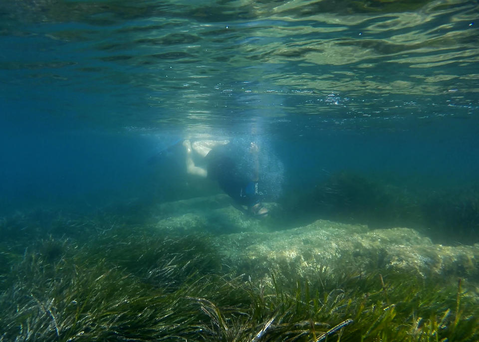 Cyprus Antiquities Department official Yiannis Violaris dives over submerged stone remains of the ancient harbor next of Amathus ancient city, in the eastern Mediterranean island of Cyprus, on Thursday, July 1, 2021. Lying just a few feet underwater a mere 200 feet off the coastline near the resort town of Limassol, this 2,400 year-old harbor said to be built Alexander the Great's successors will soon be Cyprus' newest tourist attraction where adventurous holidaymakers could snorkel over its submerged stone remains. (AP Photo/Petros Karadjias)