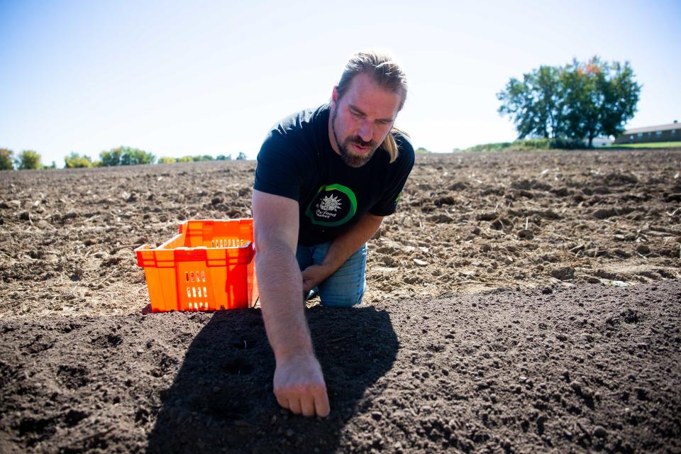 Jason Lundberg plants garlic as Kids' Food Basket celebrates the opening of its farm in Holland Township.