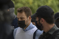 Helicopter pilot Babis Anagnostopoulos, left, escorted by police officers arrives to the prosecutor's office at a court to give evidence, in Athens, Tuesday, June 22, 2021. Anagnostopoulos was charged last Friday with the murder of his British-Greek wife, Caroline Crouch, 20, whose death he had initially claimed was caused by burglars during a brutal invasion of their home on the outskirts of Athens. (AP Photo/Petros Giannakouris)