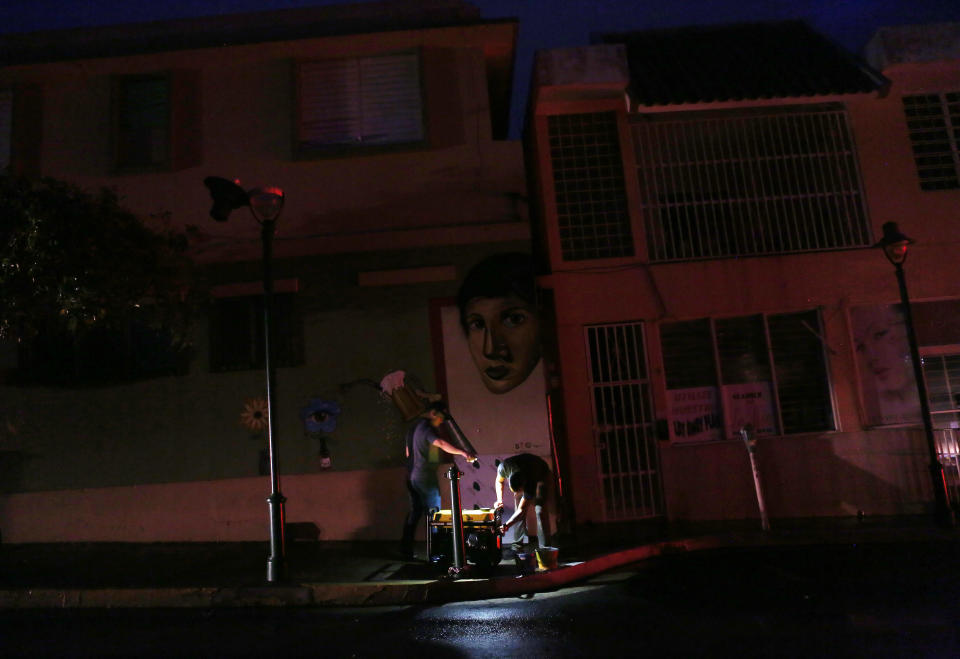 <p>A man prepares to fill a generator with gas to power a bar on a darkened street with car headlights in the distance three weeks after Hurricane Maria hit the island, on Oct. 11, 2017 in Aibonito, Puerto Rico. (Photo: Mario Tama/Getty Images) </p>