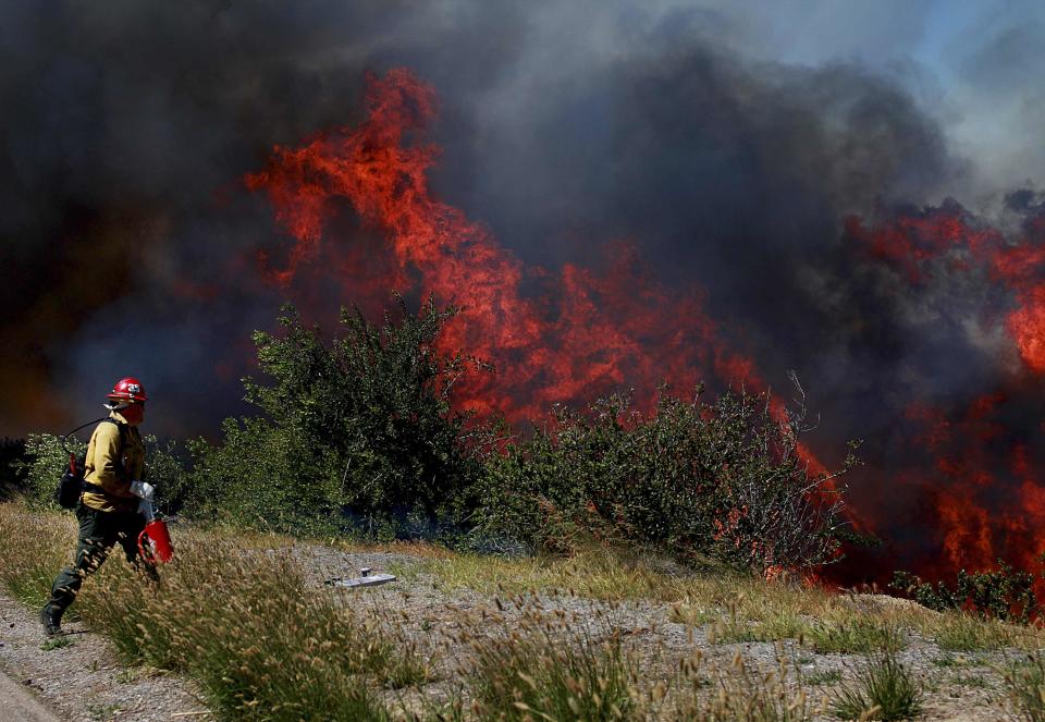 A firefighter battles the Ranch Fire near San Diego, California May 13, 2014. Several hundred acres were blackened and local schools were evacuated because of the wind-stoked flames, according to media reports. REUTERS/Sandy Huffaker (UNITED STATES - Tags: ENVIRONMENT DISASTER)